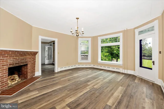 a view of an empty room with window and wooden floor