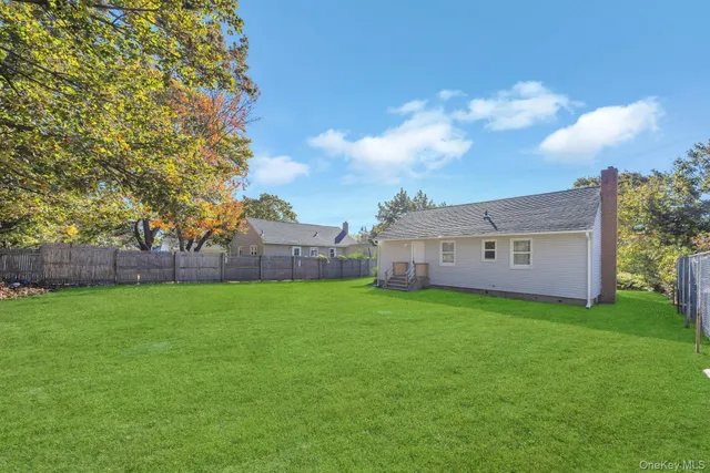 a view of a house with a big yard and large trees