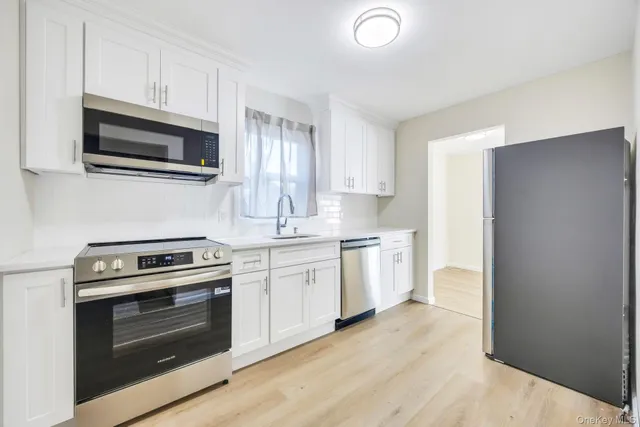 a kitchen with stainless steel appliances white cabinets and stove top oven