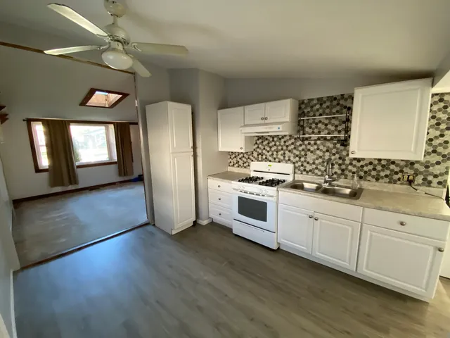 a kitchen with stainless steel appliances a white cabinets wooden floors and a fireplace
