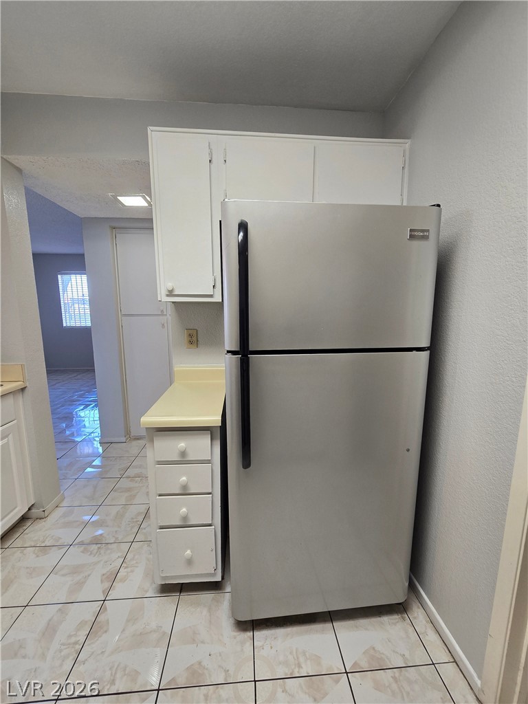 6750 Del Rey Avenue, Unit 133 Las Vegas, NV 89146 - Photo 11 of 34 A compact kitchen area features practical white cabinetry and a full-size stainless steel refrigerator.