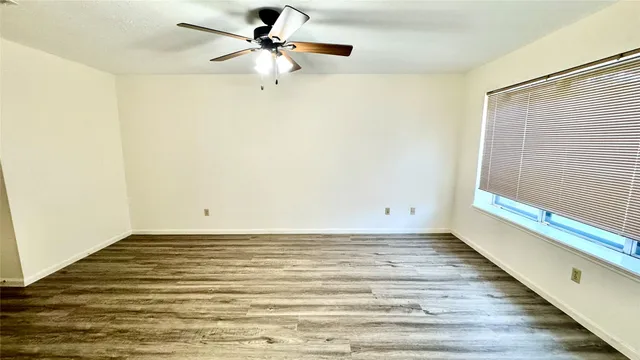 a view of a room with wooden floor and a ceiling fan