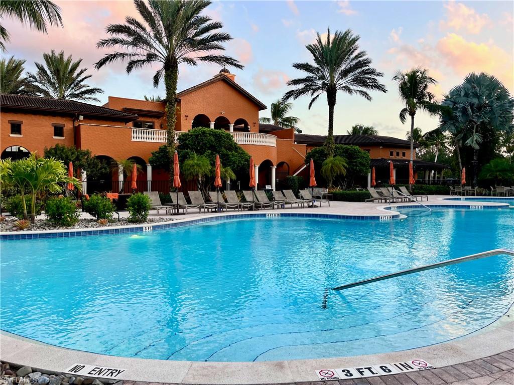 9126 Chula Vista Street, Unit 12301 Naples, FL 34113 - Photo 23 of 36 a view of a swimming pool with lawn chairs under palm trees
