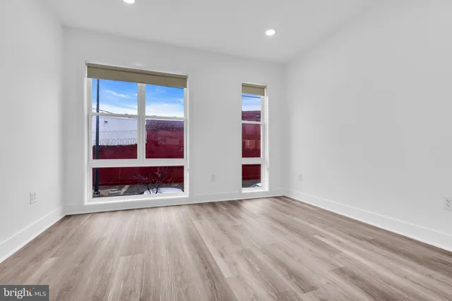 an empty room with wooden floor closet and windows