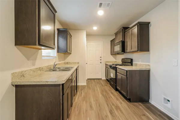 a kitchen with a sink stove top oven and refrigerator