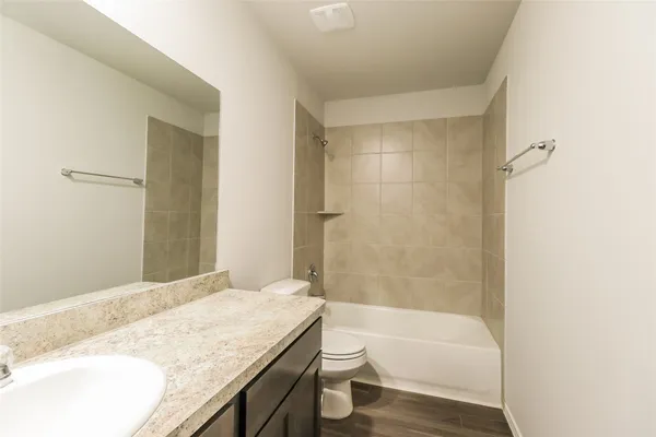a bathroom with a granite countertop sink a toilet and bathtub