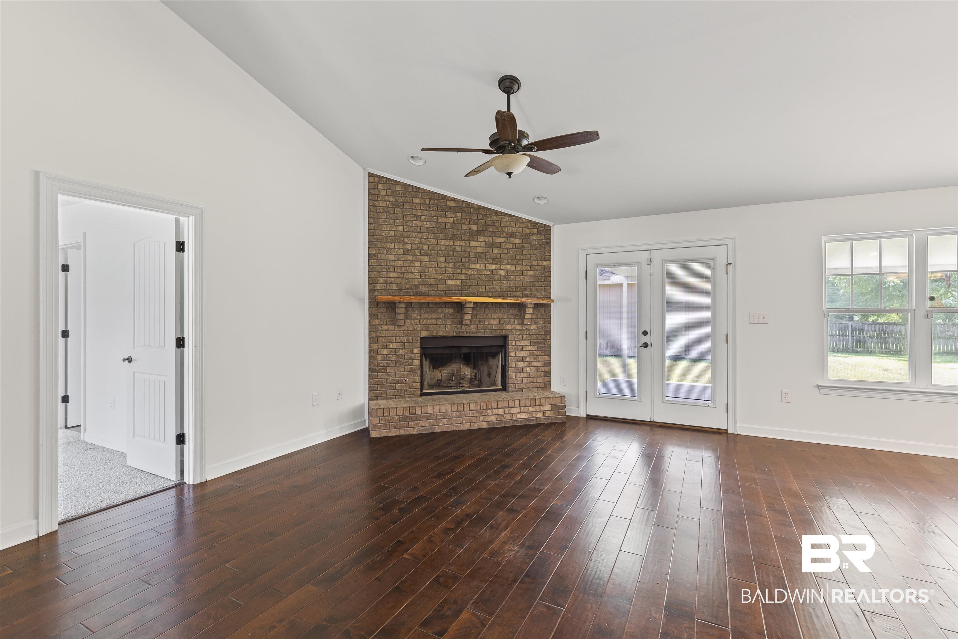 924 Brady Road North Bay Minette, AL 36507 - Photo 8 of 26 Unfurnished living room with vaulted ceiling, a brick fireplace, french doors, hardwood / wood-style flooring, and ceiling fan