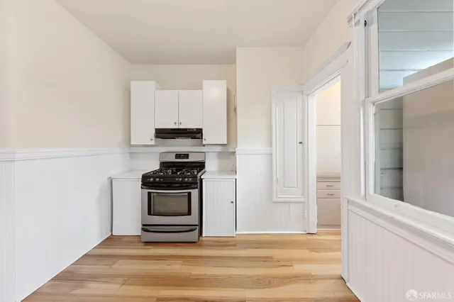 a view of empty room with wooden floor and window