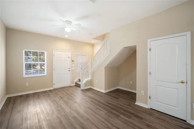 a view of an empty room with wooden floor and a window