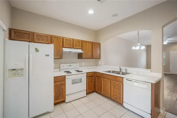 a kitchen with a sink a stove a refrigerator and white cabinets