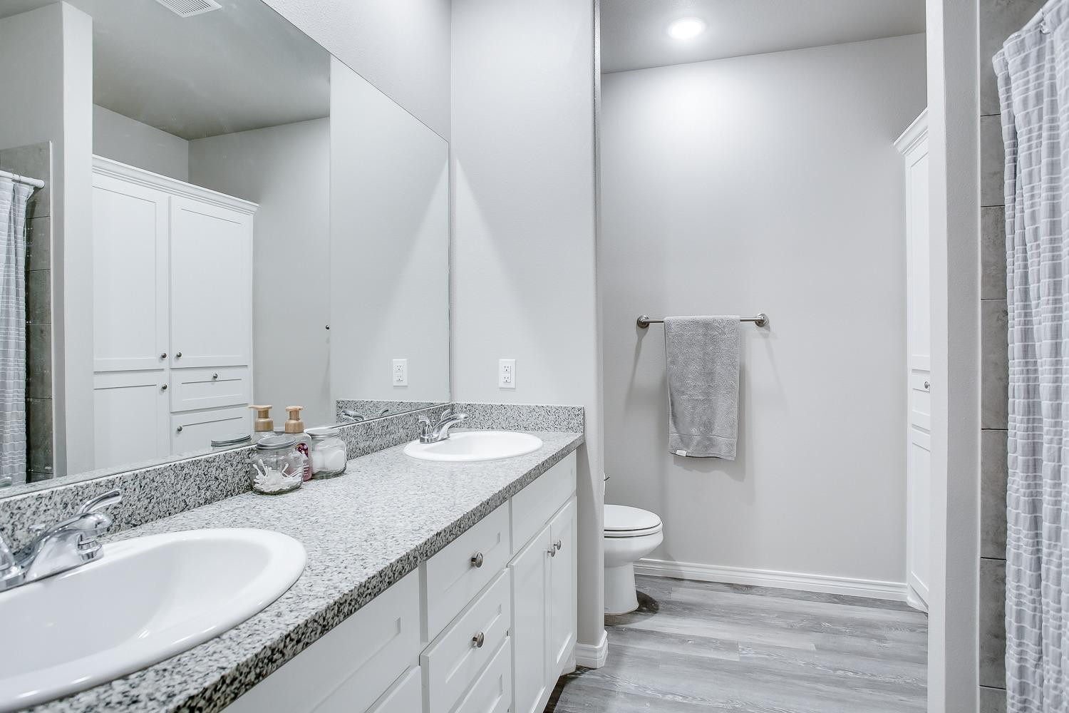 7017 10th Street Lubbock, TX 79416 - Photo 11 of 16 a bathroom with a granite countertop double vanity sink mirror and toilet