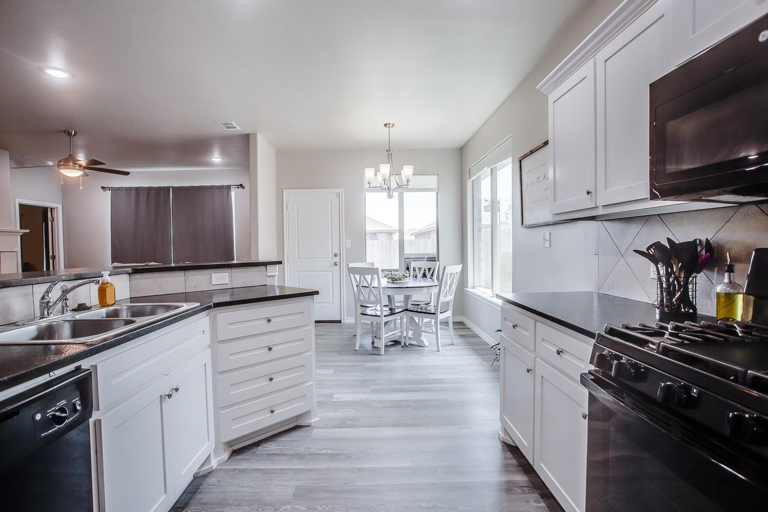 7017 10th Street Lubbock, TX 79416 - Photo 6 of 16 a kitchen with stainless steel appliances kitchen island granite countertop a sink cabinets and wooden floor