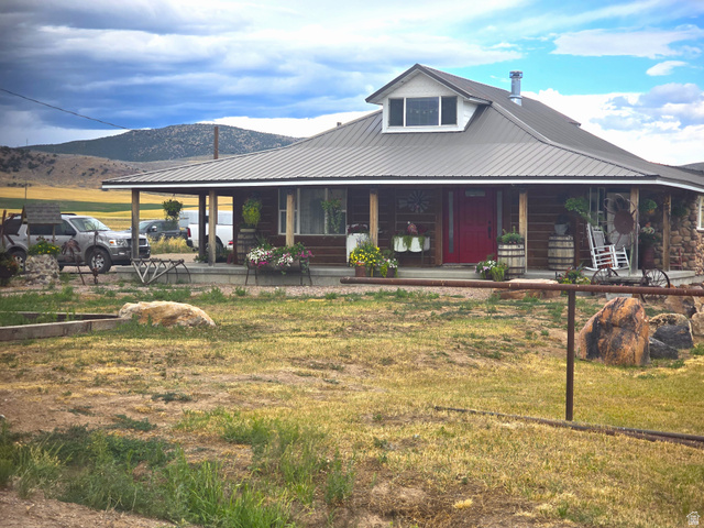 34200 Coulam Road Swan Lake, ID 83281 - Photo 1 of 24 Rustic-style residence featuring a metal roof, stone accents, and a covered porch with exposed wood columns