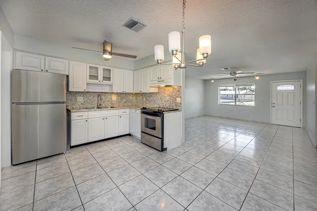 a kitchen with stainless steel appliances granite countertop a refrigerator a sink dishwasher and white cabinets with wooden floor