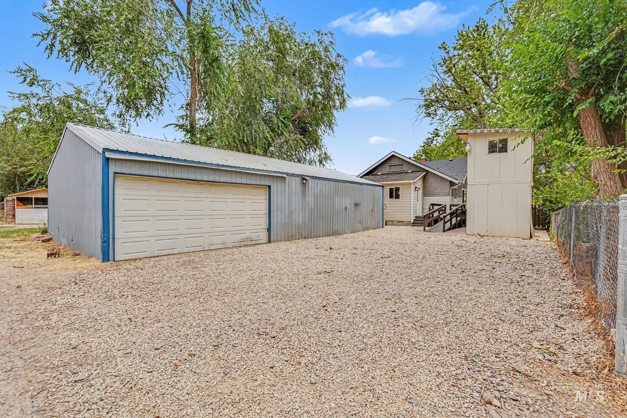 1023 State Street Weiser, ID 83672 - Photo 20 of 25 Spacious gravel lot featuring a large metal-sided outbuilding with a roll-up garage door, a separate two-story structure, and a fenced perimeter
