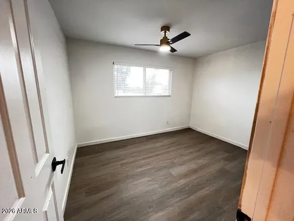 a view of empty room with wooden floor and fan