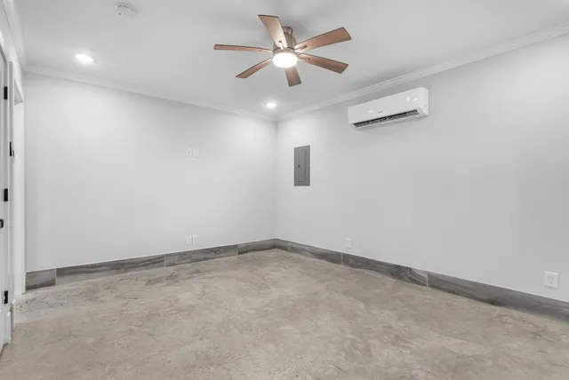 an empty room with a chandelier fan and windows
