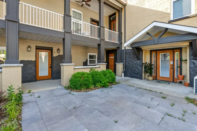 a view of a brick house with many windows next to a yard