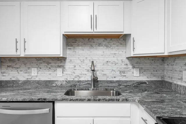 a kitchen with granite countertop a sink and a white cabinets