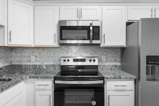 a kitchen with stainless steel appliances granite countertop white cabinets and a stove a oven with white countertops