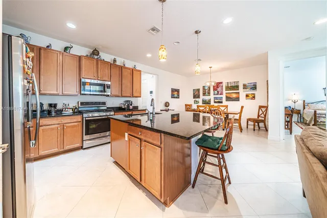 a kitchen with stainless steel appliances granite countertop a stove top oven a refrigerator a sink a dining table and chairs