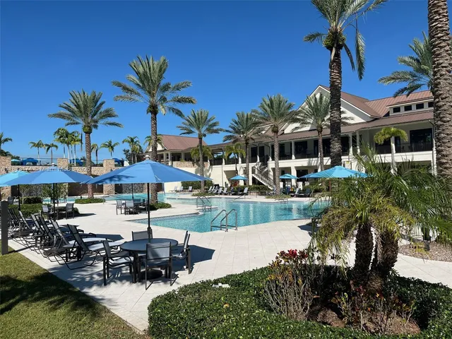 a view of a patio with table and chairs under an umbrella with palm trees