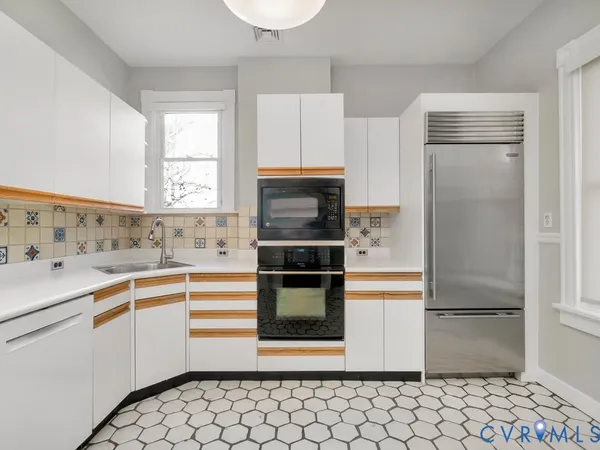 a kitchen with stainless steel appliances a stove a sink and white cabinets