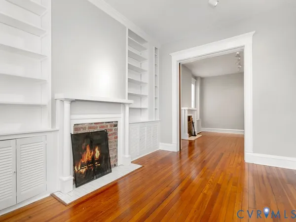an empty room with wooden floor and a fireplace