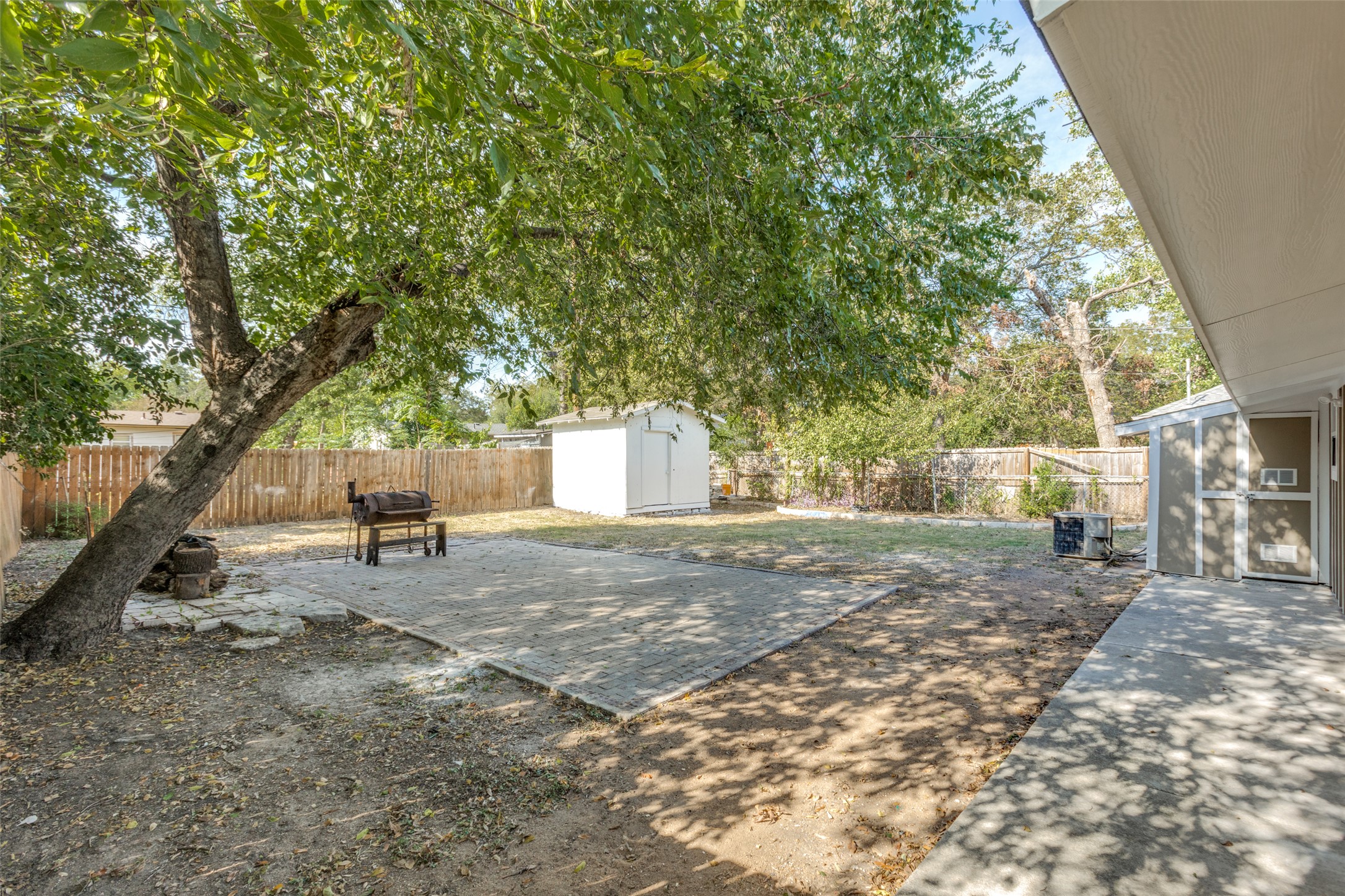 1118 Spur Street Austin, TX 78721 - Photo 14 of 21 A spacious backyard with mature trees and a paved patio area.