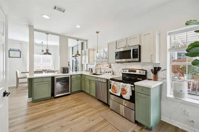 a kitchen with stainless steel appliances kitchen island granite countertop a stove top oven a sink dishwasher a dining table and chairs with wooden floor