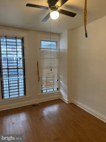 an empty room with wooden floor fan and windows