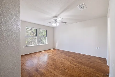 an empty room with chandelier fan and windows