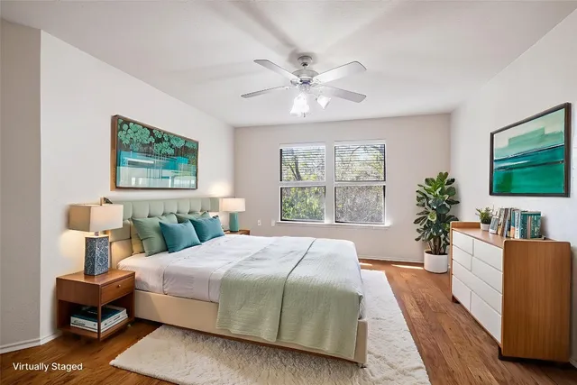 a bedroom with a large bed wooden floor and a chandelier