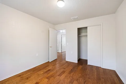 a view of an empty room with wooden floor and closet