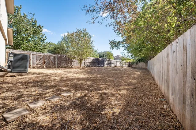 a view of a backyard with large trees and wooden fence