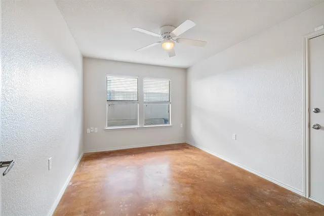 an empty room with windows and ceiling fan