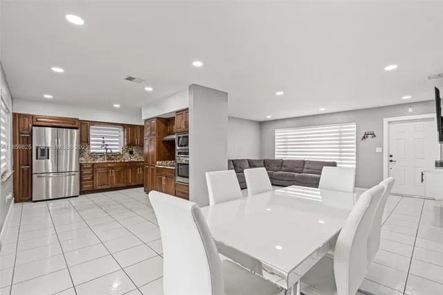 a large white kitchen with a large window and stainless steel appliances
