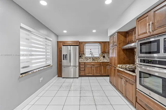a kitchen with stainless steel appliances kitchen island granite countertop a stove a sink and a refrigerator