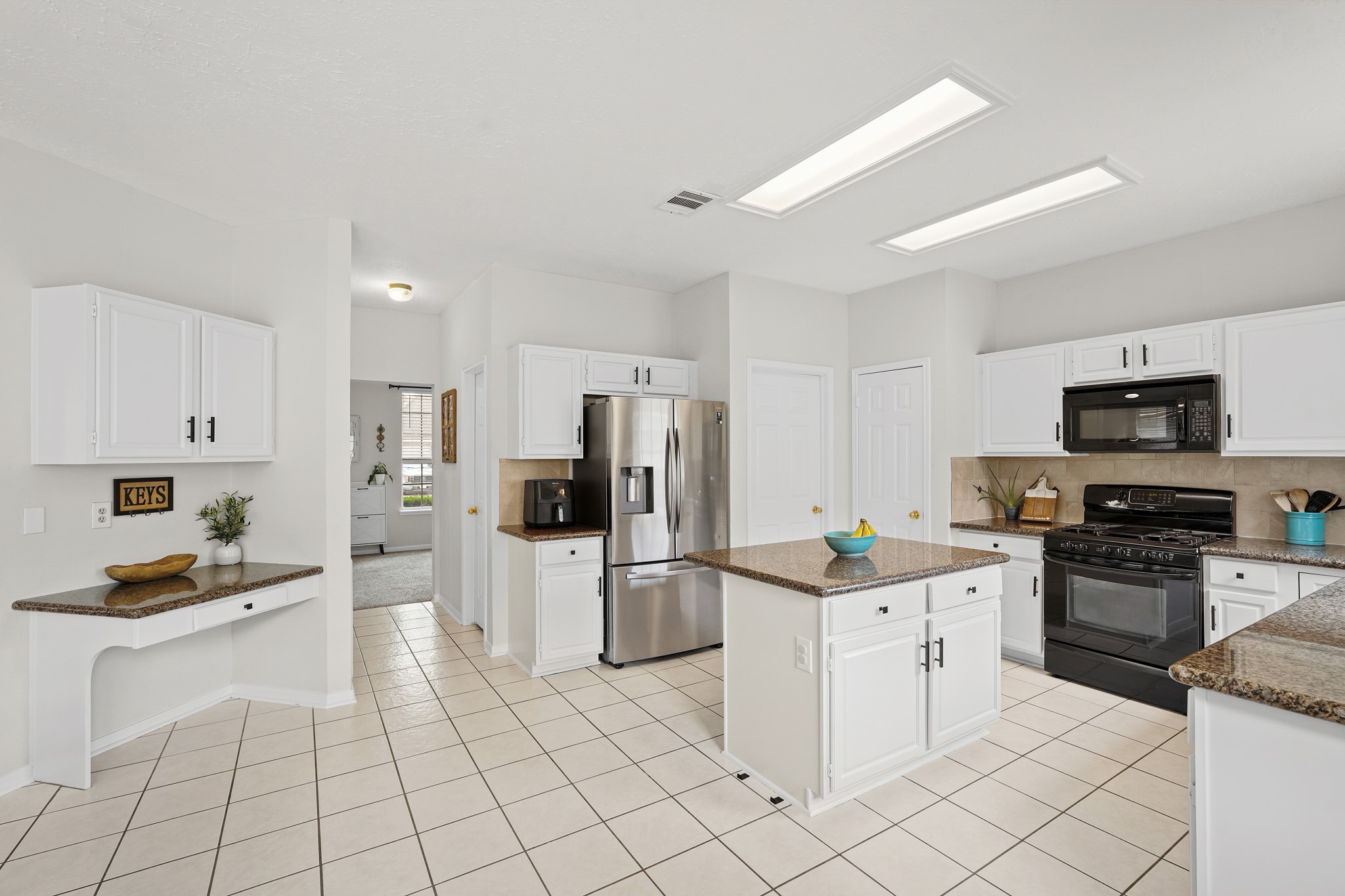 16114 Kintyre Point Road Houston, TX 77095 - Photo 25 of 44 This kitchen features modern appliances, spacious white cabinetry, and a central island with granite countertops. It has tiled flooring and ample overhead lighting, offering a bright, functional space.