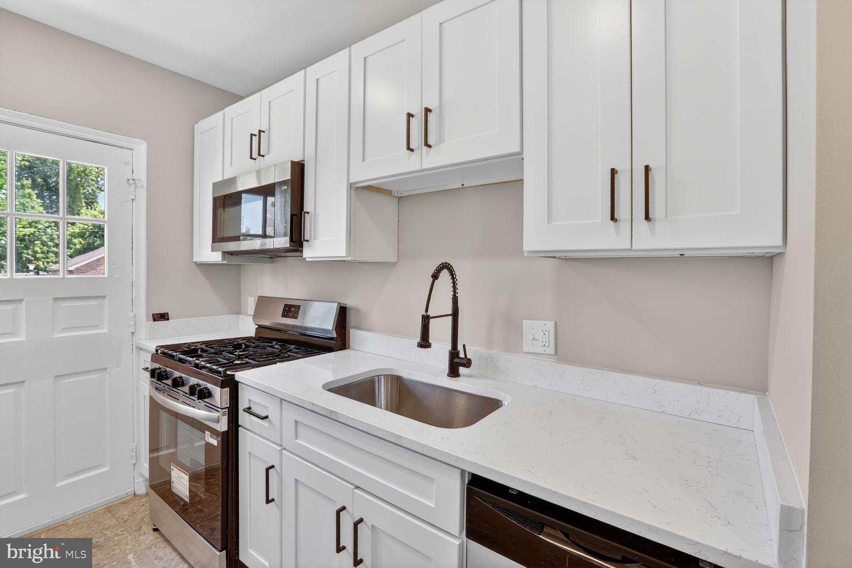 315 East Cold Spring Lane Baltimore, MD 21212 - Photo 4 of 25 a kitchen with granite countertop a sink a stove and cabinets