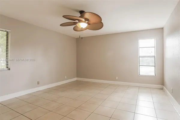 an empty room with a chandelier fan and windows