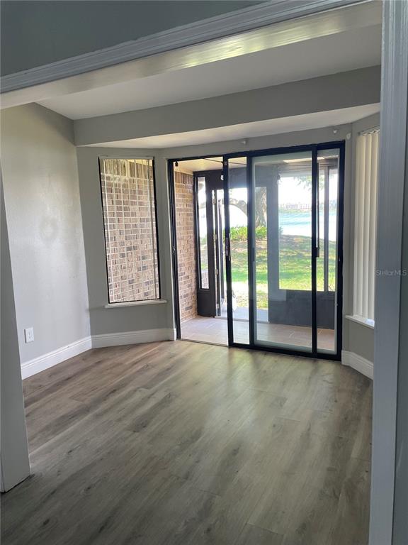 7652 Spring Bay Cove, Unit 3 Orlando, FL 32819 - Photo 25 of 30 a view of an empty room with wooden floor and a window
