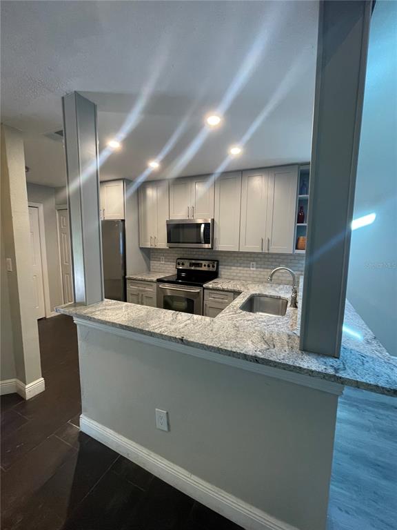 7652 Spring Bay Cove, Unit 3 Orlando, FL 32819 - Photo 5 of 30 a kitchen with stainless steel appliances granite countertop a sink a stove a refrigerator a microwave oven with cabinets