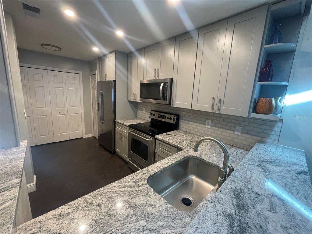 7652 Spring Bay Cove, Unit 3 Orlando, FL 32819 - Photo 7 of 30 a kitchen with stainless steel appliances granite countertop a sink stove and refrigerator