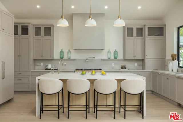 a kitchen with kitchen island granite countertop a sink a counter top space appliances and cabinets