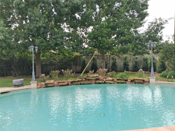 a view of a lake with lawn chairs and large trees