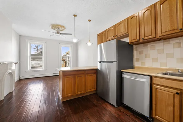 a kitchen with stainless steel appliances granite countertop a refrigerator a sink dishwasher and wooden cabinets with wooden floor