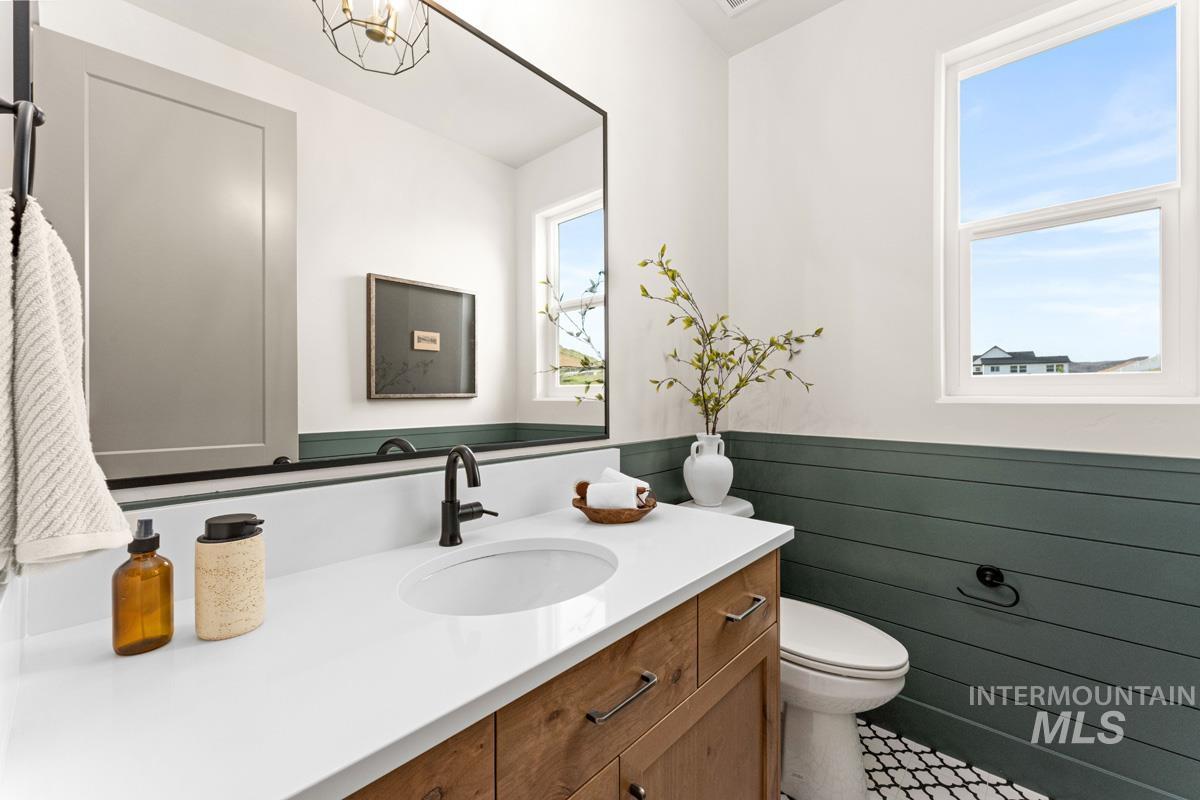 13338 North Spring Creek Way Boise, ID 83714 - Photo 13 of 46 Bathroom featuring a wood-finish vanity with a white countertop and undermount sink, black fixtures, and a large wall-mounted mirror