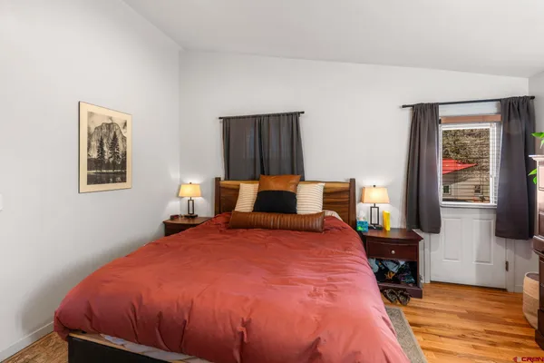 a bed sitting in a bedroom next to a window with pc on the table and a flat screen tv