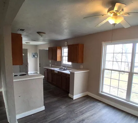 a large kitchen with a window and wooden floor
